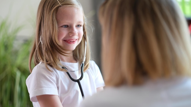 Der Hausarzt lässt ihre junge Patientin mit dem Stethoskop-Konzept der Kindergesundheit spielen und