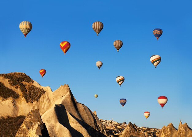 Der Heißluftballon steigt sehr hoch in den blauen Himmel über den weißen Wolken, die helle Sonne scheint