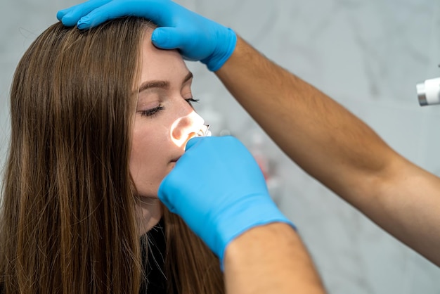 Foto der hno-arzt untersucht die nase des patienten mit einem otoskop medizinische untersuchung der nase gesundheits- und medizinkonzept