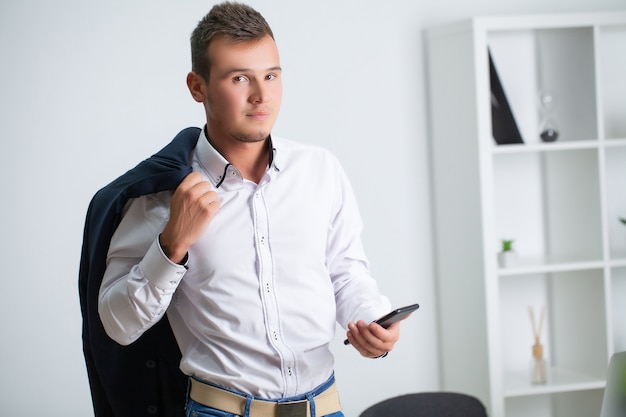 Der hübsche junge Arbeiter benutzt ein Telefon im Firmenbüro