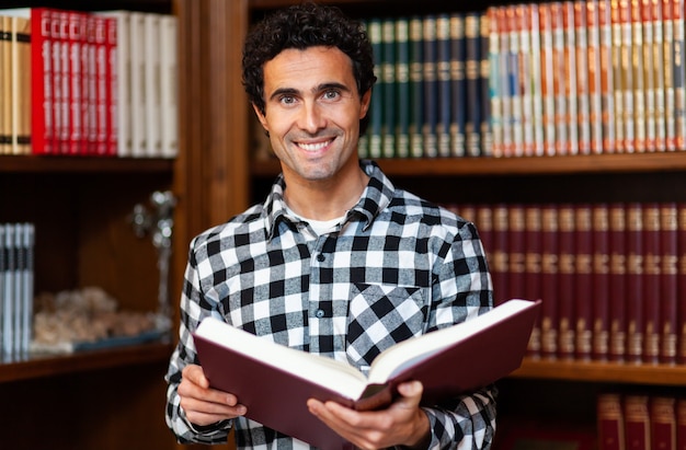 Der hübsche Mann steht an den Bücherregalen