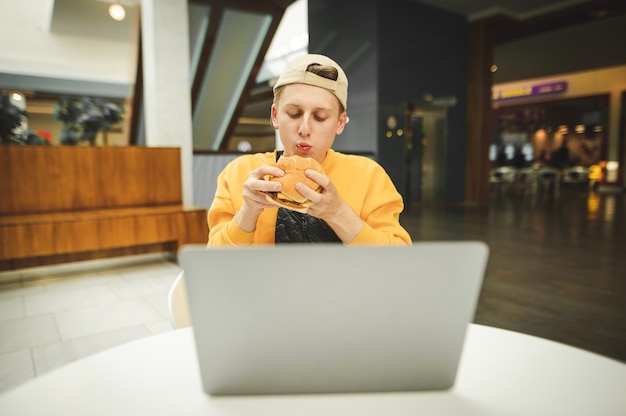 Der hungrige Freiberufler isst einen Burger in einem Fast-Food-Restaurant