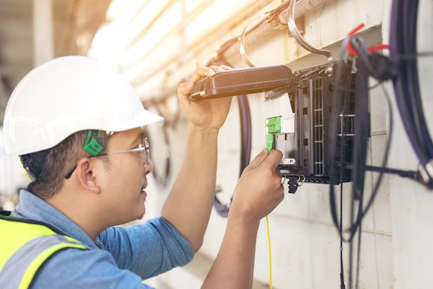 Der Ingenieur repariert den Anschluss der Fasern an der Splitterwanne aus der Nähe von außen