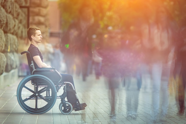 Der Invalide sitzt im Rollstuhl im Menschenstrom auf der Straße