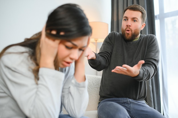 Der irritierte Ehemann schreit mit Gewalt auf seine Frau, die Frau bedeckt ihr Gesicht vor Angst.