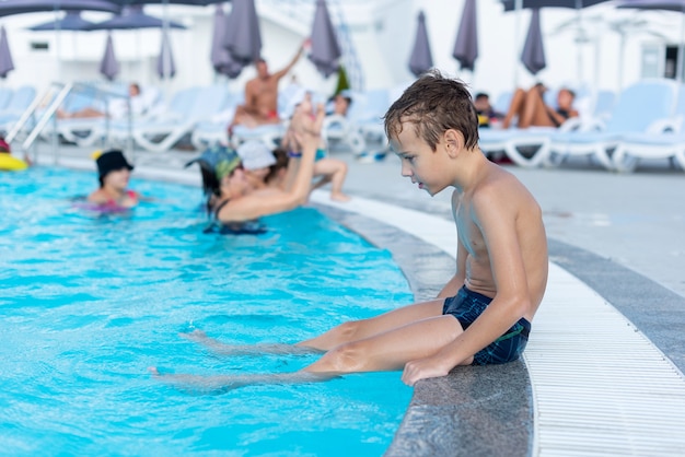 Der Junge am Beckenrand lächelt Das Freibad