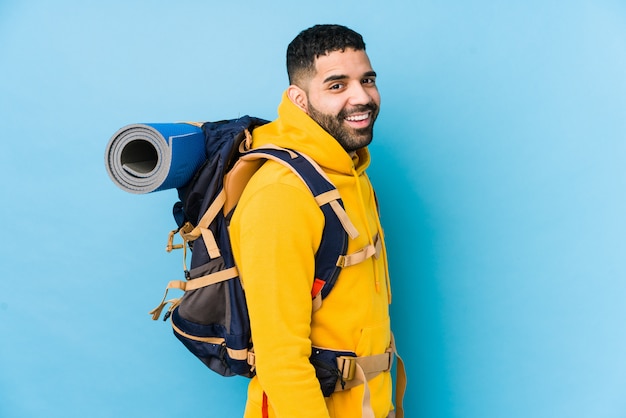 Der junge arabische Reisende Backpacker Mann schaut lächelnd, fröhlich und angenehm zur Seite.