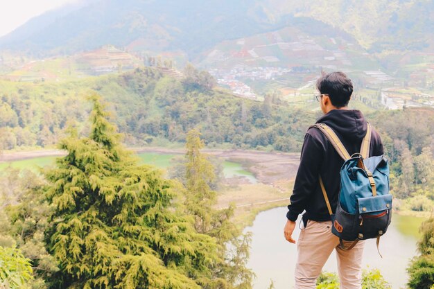 Der junge asiatische Rucksacktourist ist glücklich und genießt es, in den Bergen zu reisen