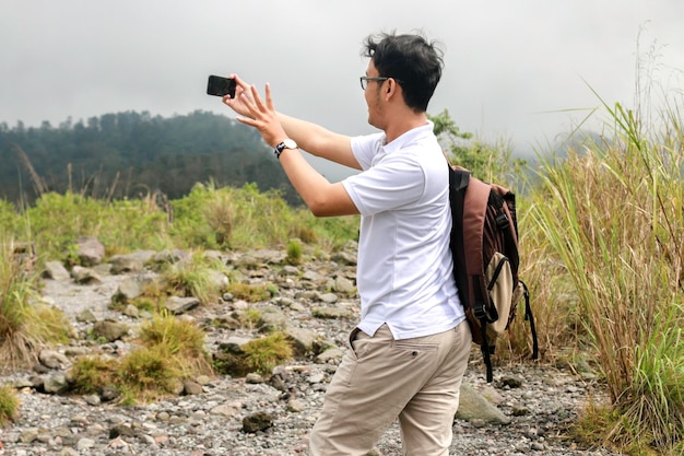 Der junge asiatische Rucksacktourist macht gerne Vlog oder Video mit dem Smartphone, wenn er in den Bergen unterwegs ist