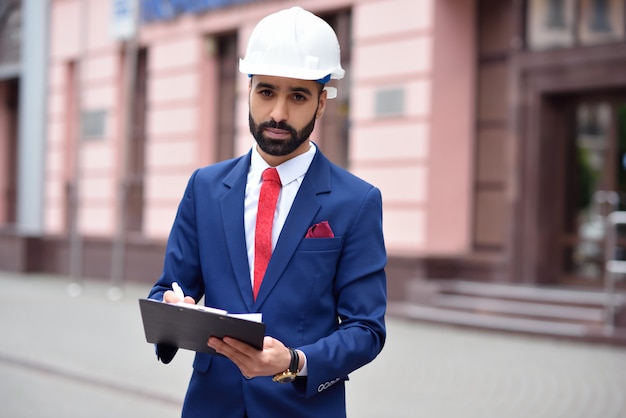 Der junge bärtige Ingenieur macht sich Notizen auf seiner Zwischenablage