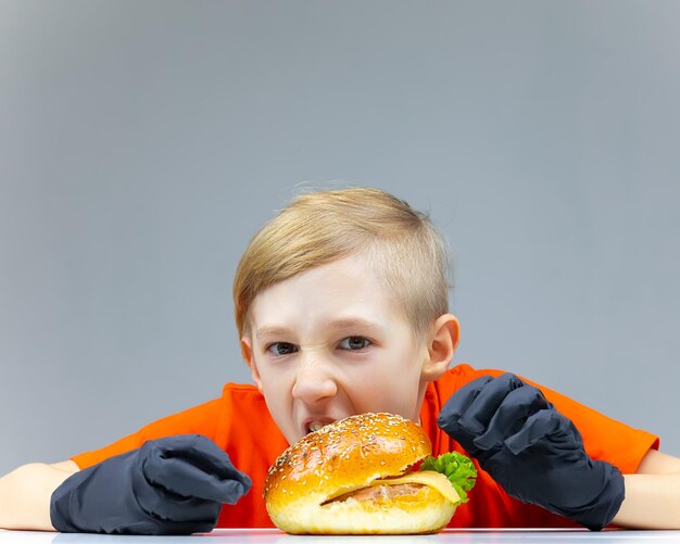 Der Junge beugt sich über den Burger und will hineinbeißen