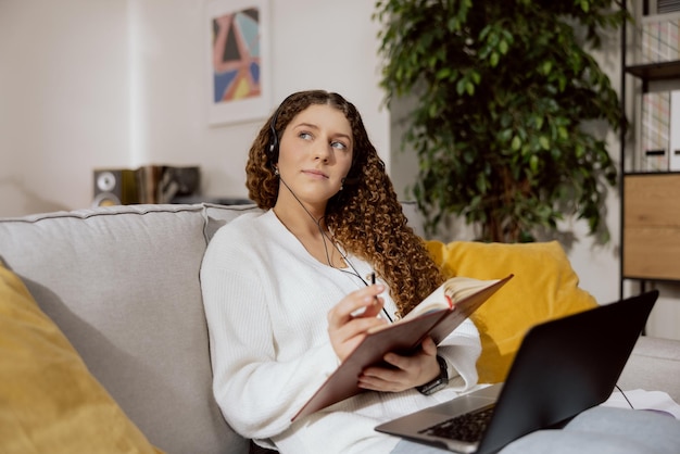 Der junge Callcenter-Mitarbeiter, der von zu Hause aus arbeitet, sitzt im Wohnzimmer auf einem grauen Sofa