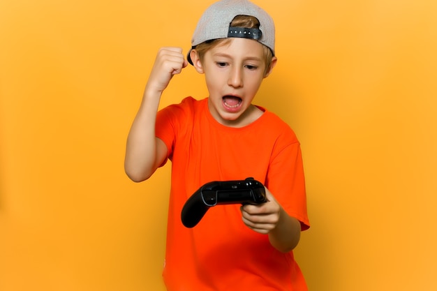 Der junge Computerspieler freut sich über den Sieg, hält einen Joystick in der Hand und hebt sie hoch