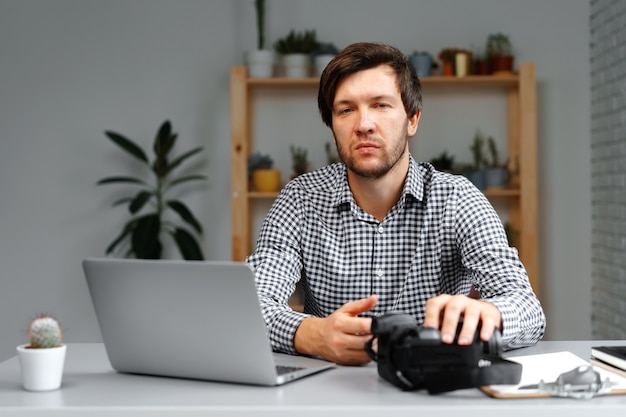 Der junge Fotograf sitzt am Tisch und arbeitet von zu Hause aus