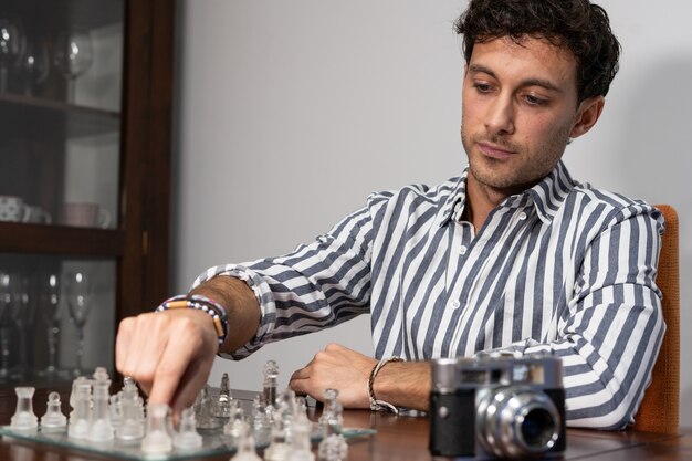 Der junge Fotograf spielt eine Partie Schach mit einer Kamera neben sich