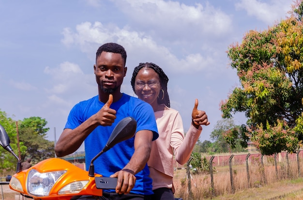 Der junge gutaussehende afrikanische Motorradfahrer und sein Kunde waren beide aufgeregt und machten Daumen hoch