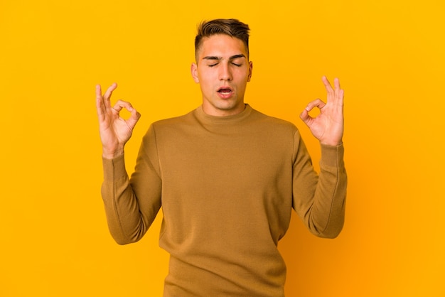 Der junge gutaussehende kaukasische Mann, der isoliert ist, entspannt sich nach hartem Arbeitstag, er führt Yoga durch.