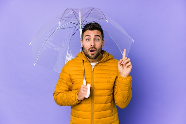 Der junge gutaussehende Mann, der einen Regenschirm hält, lokalisierte das Haben irgendeiner großartigen Idee, Konzept der Kreativität.