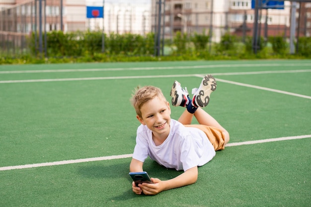 Der Junge hält das Telefon und schaut weg