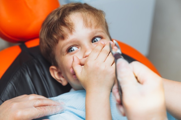 Der Junge hat Angst vor dem Zahnarzt mit Zangen Das Kind hat Angst, den Zahn zu entfernen Der Teenager weigert sich, seine Zähne zu behandeln Konzept der Kinderzahnheilkunde