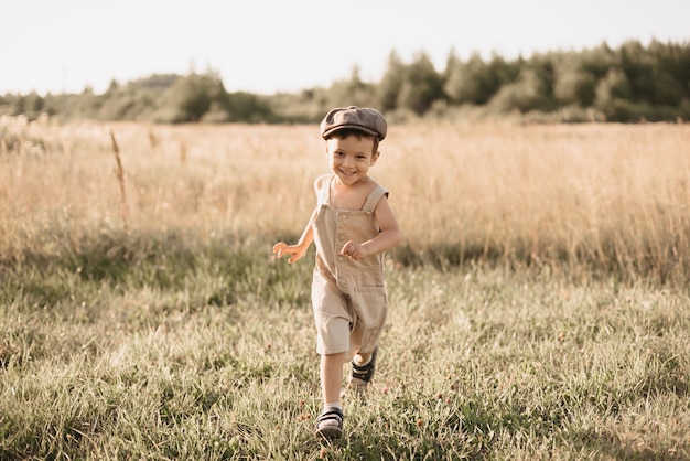 Der Junge hat Spaß und läuft aktiv auf dem Feld Ein fröhlicher und aufrichtig jubelnder Junge Kindheit auf dem Land