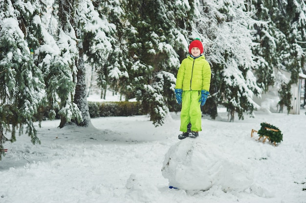 Der Junge im Schnee im Park. Ein Junge spielt im Winter Park. Entzückendes Kind, das in Schneewinterwald geht