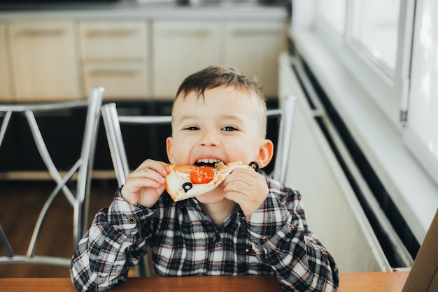 Der Junge in der Küche zu Hause isst Pizza mit Lachs