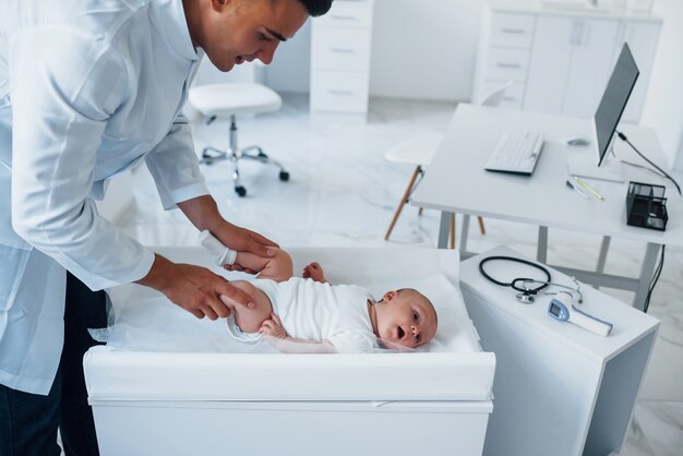 Der junge Kinderarzt ist tagsüber mit dem kleinen Baby in der Klinik.