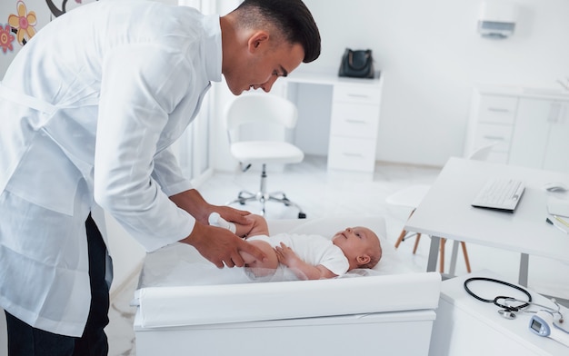 Der junge Kinderarzt ist tagsüber mit dem kleinen Baby in der Klinik.