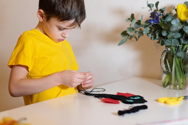 Der Junge macht Handarbeiten Nähen eines weichen Spielzeugs aus Filzhänden Nahaufnahme Zeitvertreib zu Hause