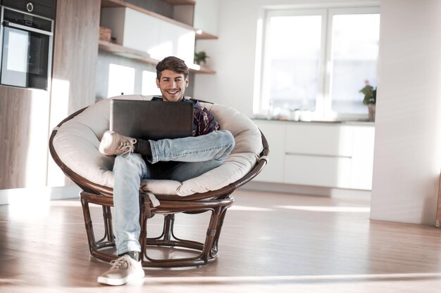 Der junge Mann benutzt einen Laptop in seiner modernen Wohnung