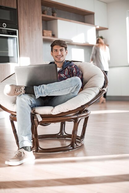 Der junge Mann benutzt einen Laptop in seiner modernen Wohnung