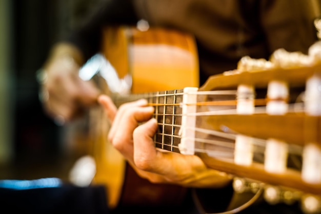 Der junge Mann, der eine akustische Gitarre spielt, schießt mit Hintergrundbeleuchtung