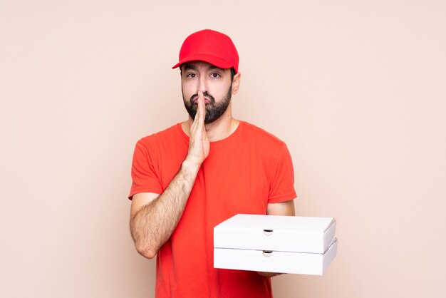 Der junge Mann, der eine Pizza über lokalisiert hält, hält Palme zusammen. Person bittet um etwas