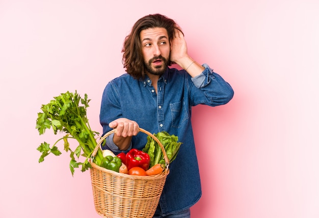 Der junge Mann, der organisches Gemüse von seinem Garten auswählt, lokalisierte das Versuchen zum Hören eines Klatsches.