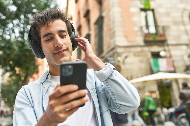 Der junge Mann genießt den Komfort mobiler Musik mit Kopfhörern und seinem Smartphone