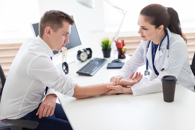 Der junge Mann kam zum Arzt. Der Arzt misst den Puls des Patienten