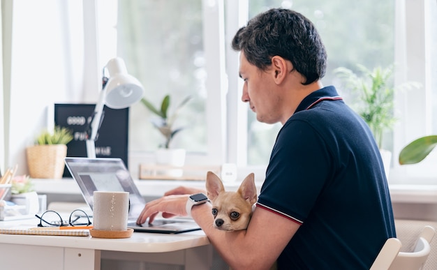 Der junge Mann mit Hund c, der auf Laptop tippt