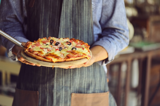 Der junge Mann serviert heiße Pizza.