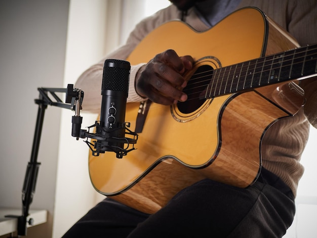 Der junge Mann singt und spielt Gitarre, während er zu Hause eine Audioaufnahme macht