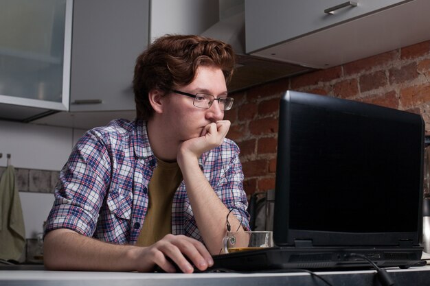 Der junge Mann sitzt an einem Laptop.