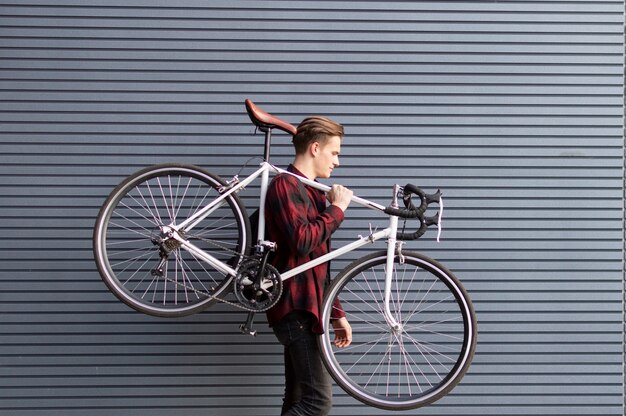 Der junge Mann trägt ein kaputtes Fahrrad auf den Schultern