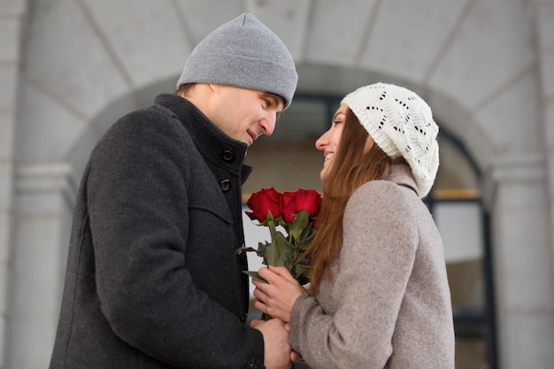 Der junge Mann überraschte seine Freundin mit einem Rosenstrauß in der Stadt. Valentinstag. Stehend und einander ansehend. Hochwertiges Foto