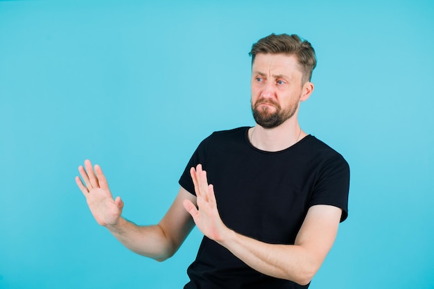 Foto der junge mann zeigt eine stopp-geste, indem er seine handvoll auf blauem hintergrund erhebt