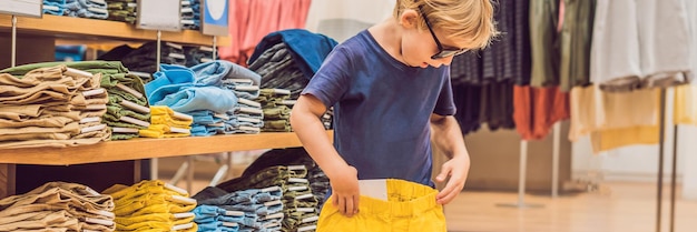 Der Junge probiert Kleidung im Kinderbekleidungsgeschäft BANNER an, Langformat