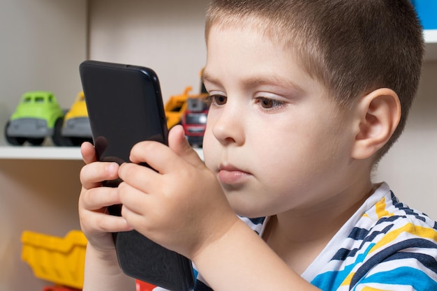 Der Junge schaut aufmerksam auf den Telefonbildschirm