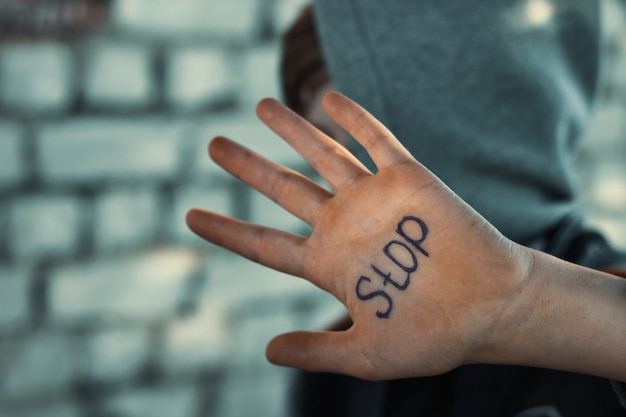 Foto der junge schließt seine hand, geschrieben auf seine hand, grausamkeit gegenüber kindern