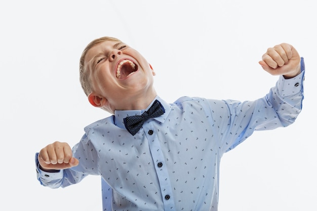 Der Junge schreit emotional. Kind 9-10 Jahre alt in einem blauen Hemd. Schwierigkeiten bei der Kommunikation und beim Lernen. Weißer Hintergrund.