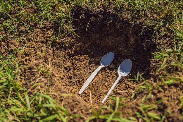 Der Junge spielt Recycling. Er vergräbt Plastik-Einweggeschirr und biologisch abbaubares Geschirr