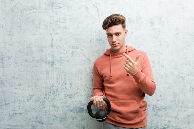 Der junge Sportmann, der einen Dummkopf zeigt mit dem Finger auf Sie hält, als ob Einladung näher kommen.